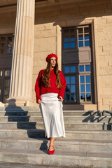 Woman Red Beret Steps Building Morning Fashionable. Dressed girl descends sunlit stairs of classic...