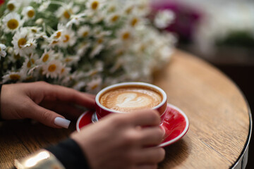 Coffee Flowers Cafe: Morning latte art held on a wood table with daisy bouquet, relaxation time.