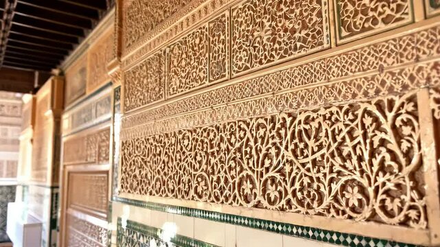 A close-up of the ornate tile work and carvings in the Alhambra, showcasing the delicate and detailed Islamic art on the walls