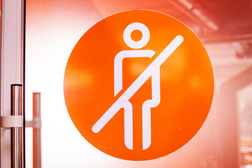 round orange schematic sign of a person prohibiting entry into these doors