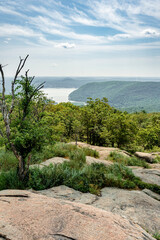 Stony Point, NY - US - Jul 3, 2025 From a rocky, elevated perch in Bear Mountain State Park, a scenic overlook reveals tree-covered mountains, the Hudson River, and a hazy sky dotted with clouds.