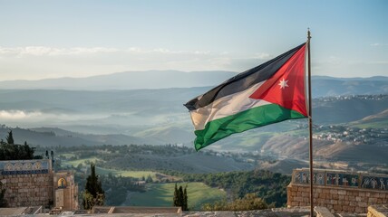 Flag Jordan waving majestically over Mount Nebo with panoramic valley vista and layered misty mountains