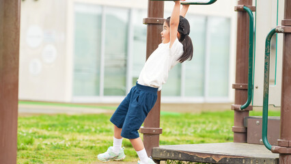 公園の雲梯で遊ぶ女の子