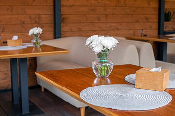 cozy stylish tables with white chrysanthemums in the restaurant outside