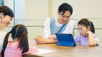タブレットを見る女の子と使い方を教える男性