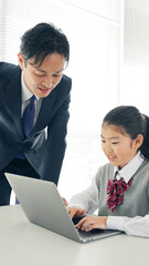女の子にパソコンの使い方を指導する男性教師