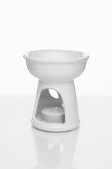 White ceramic aroma lamp with tealight candle on white background