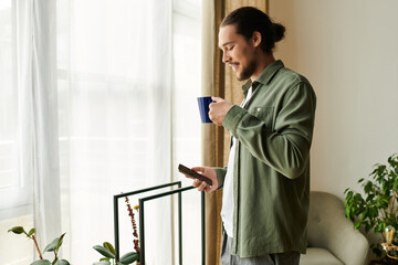 Young man enjoying a moment of relaxation at home while holding a cup and checking his phone