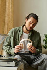 Young handsome man enjoying music at home while relaxing on a cozy afternoon