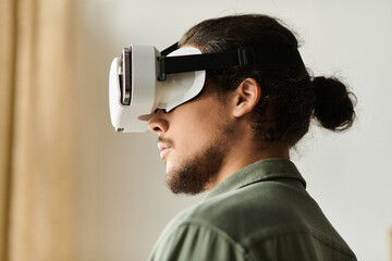 Young man enjoying a virtual reality experience while relaxing at home during the afternoon