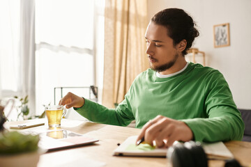 Young handsome man enjoying a cup of tea while working at home during a sunny afternoon