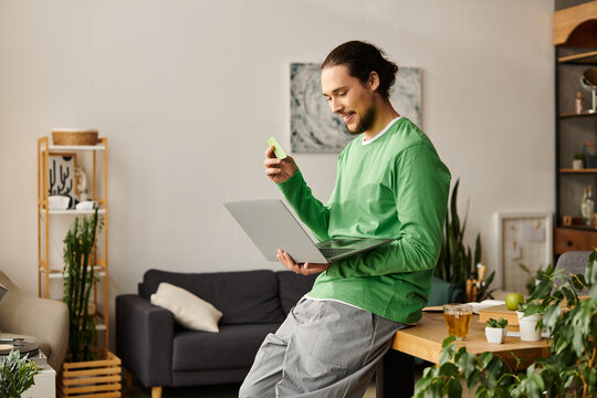 Young man enjoying leisure time at home while working on his laptop and snacking - Powered by Adobe