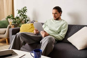 Relaxing at home, a young handsome man engrossed in reading on a cozy sofa