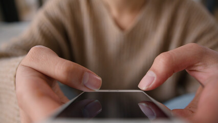 Cropped shot woman using mobile phone touch screen scrolling browsing internet app gadget addicted...