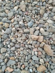 A close-up image of natural volcanic gravel stones with various colors and rough textures, commonly used in construction, landscaping, and decoration.