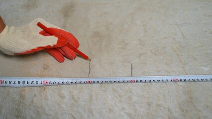 Construction worker marking surface with pencil and measuring tape