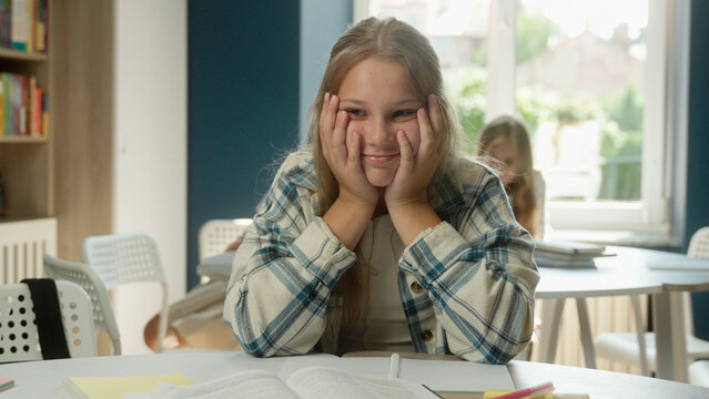 Stressed tired Caucasian teen girl teenager student schoolgirl exhausted sad child kid pupil difficult studying in classroom boring school education looking at camera bored sad learn lesson hard task