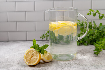 Refreshing Lemon Water in a Glass Pitcher on Concrete Background,Glass pitcher filled with fresh...