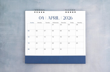April 2026 desk calendar on gray cement wall background. Page of annual monthly calendar for your...