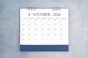 November 2026 desk calendar on gray cement wall background. Page of annual monthly calendar for...