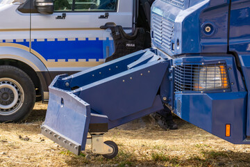 Barricade removal device mounted on a police vehicle, side view on dry ground in daylight