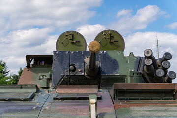 Front view of an armored vehicle turret with an automatic cannon, set against a cloudy sky.