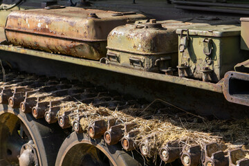 rusty fuel tanks and tracks of an old military vehicle covered with straw remains – abandoned...