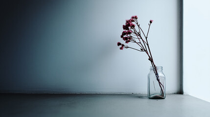 Dried pink flowers in glass jar on minimalist blue background