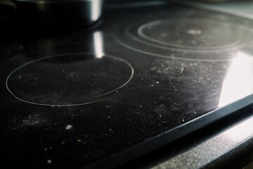 Black glass stovetop with fingerprints, grease smears, and cooking residue in soft daylight Generative AI