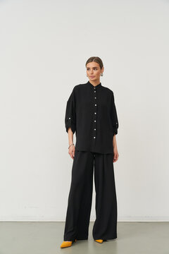 Stylish woman standing in a modern indoor studio wearing elegant black outfit