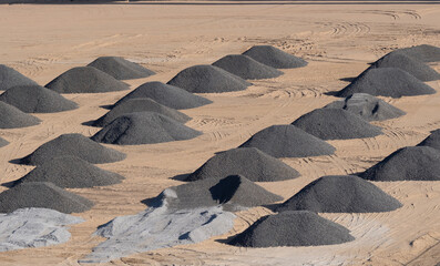 Excavators level the site with sand, moving sand from the mounds.