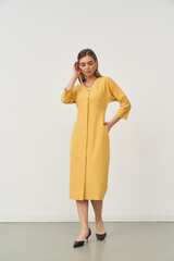 Fashionable woman posing in stylish mustard dress in an indoor studio setting
