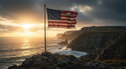 Dramatic american flag flies atop rugged coastal cliffs during golden hour light