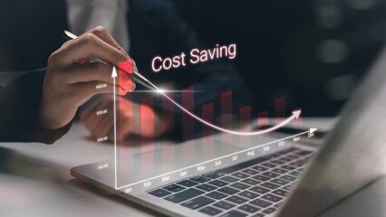 A businessman using a pen to indicate a rapid cost-saving strategy with a digital graph on a laptop. Concept of expense reduction, smart budgeting, and financial efficiency.