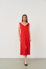 Stylish woman poses in a sleek red dress in a minimalistic indoor studio setting