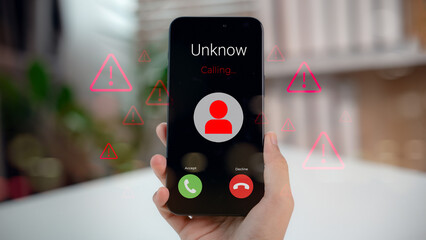 Hand holding smartphone showing unknown caller with red alert icons, representing phone scam, fraud...