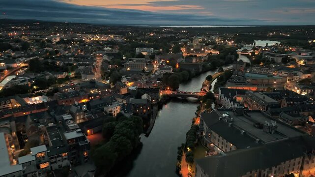 Stunning aerial shot of Galway cityscape at dusk with views over the River Corrib and vibrant lights illuminating the historic buildings and bridges. Night view of Galway, Ireland