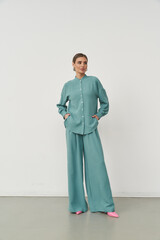 Stylish woman modeling modern clothing in a minimalistic indoor studio setting