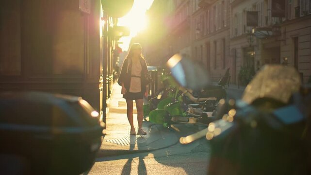 Woman tourist walks through romantic streets of Paris at sunset. Beautiful architecture of historic streets of the capital of France, girl on a trip through a beautiful European city.