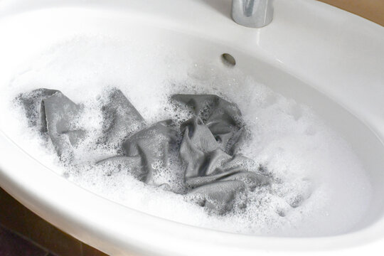 Washing clothes in the basin or sink.