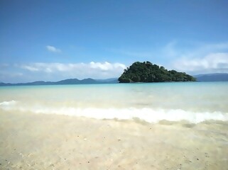 Tropical island with clear turquoise sea and white wave under blue sky, paradise beach in Southeast...