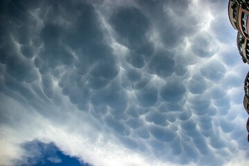 Big blue round clouds before rain in cloudy sky above house
