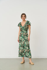 Fashionable female model showcases stylish green dress in an indoor studio setting