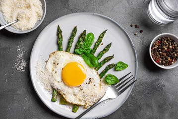 Fried egg with green asparagus and grated parmesan cheese for breakfast