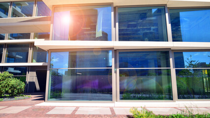 City life, urban landscape and ecology.  Modern office complex with glass facades and smooth lines against backdrop of green trees, concept of modern architecture. Organically building into nature.  