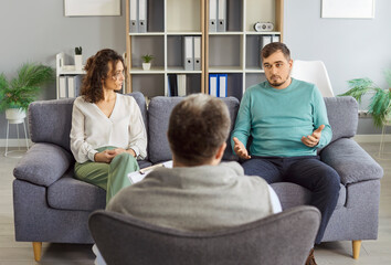 Family couple engages in conversation with psychologist during therapy session, receiving...