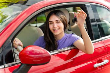 Young woman showing car keys from red car window
