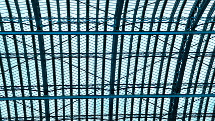 Symmetrical industrial ceiling pattern showing steel beams and glass light
