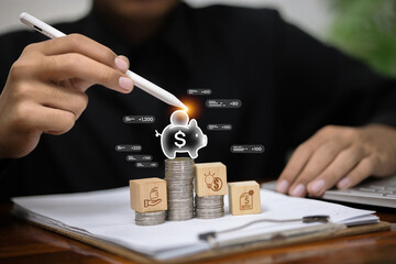 A person uses a stylus to add to a digital piggy bank sitting on stacks of coins