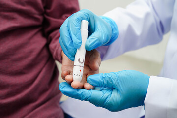 Asian senior woman using lancet pen on senior patient finger for check sample blood sugar level to treatment diabetes.